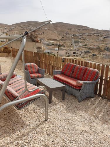 eine Terrasse mit 2 Stühlen, einem Sofa und einem Tisch in der Unterkunft The Little B&B on the Hill in Wadi Musa