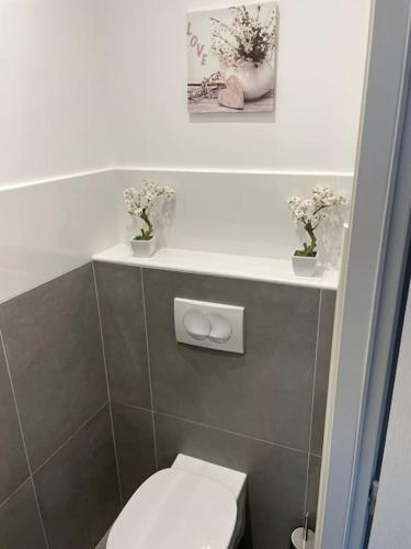 - une salle de bains avec des toilettes et des fleurs sur une étagère dans l'établissement Cocon 4 pers vue mer, à Menton