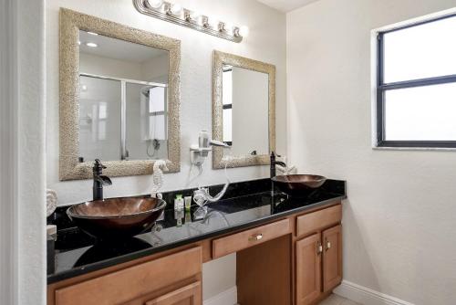 a bathroom with two sinks and two mirrors at Spacious 4BR Home Perfect for Families in Orlando