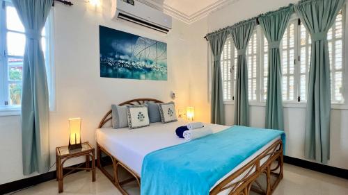 Schlafzimmer mit einem Bett mit blauer Bettwäsche und Fenstern in der Unterkunft Chalet Saffron Goa in Benaulim