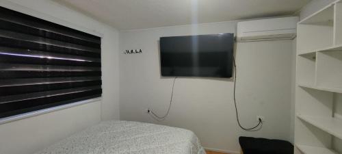 a bedroom with a flat screen tv on the wall at Acogedora habitación en curico in Curicó