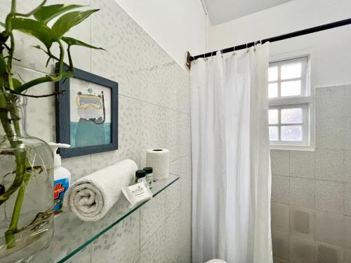 ein Bad mit einem weißen Duschvorhang und einem Fenster in der Unterkunft Chalet Saffron Goa in Benaulim