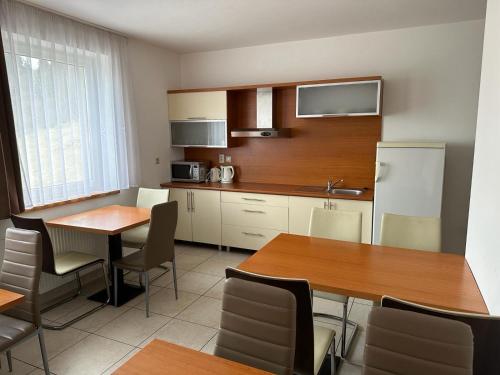 a kitchen with two tables and a refrigerator at Penzión Uhliská in Nižná