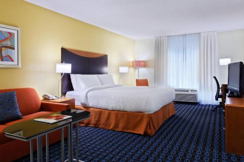 a hotel room with a bed and a couch at Fairfield Inn & Suites Charlotte Arrowood in Charlotte