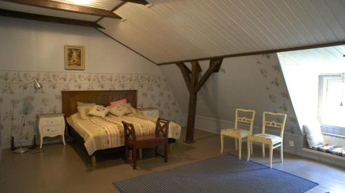 a bedroom with a bed and two chairs in it at Pehtoorin Kammarit in Iltasmäki