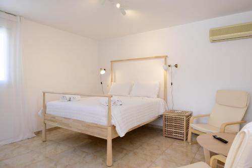 a white bedroom with a bed and a chair at Summer Retreat Sea View 4th floor in Agios Nikolaos