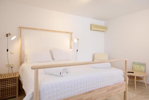 um quarto com uma cama branca com uma estrutura em madeira em Summer Retreat Sea View 4th floor em Agios Nikolaos