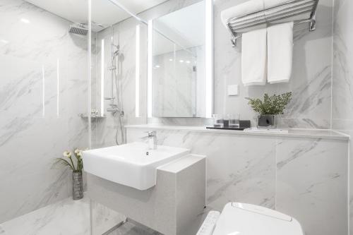 een witte badkamer met een wastafel en een toilet bij Centum Prime Hotel in Busan