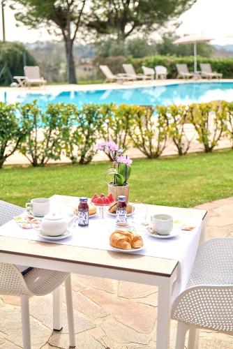- une table blanche avec de la nourriture et des boissons à côté de la piscine dans l'établissement Moniga Resort, à Moniga del Garda