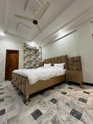 a bedroom with a large bed and a ceiling fan at Hotel Flower of Capital in Islamabad