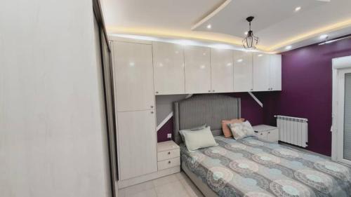 um quarto com uma cama com paredes roxas e armários brancos em Appartement pour vacances em Boumerdès