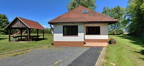 a small house with a gazebo in a field at Domki nad strumykiem in Mirsk