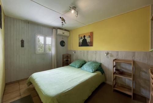 een slaapkamer met een bed en een gele muur bij Relais du Volcan in La Plaine des Cafres