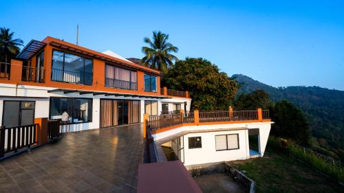a house with a balcony with a view of it at Jungle Drive Resort Vayalada in Kozhikode