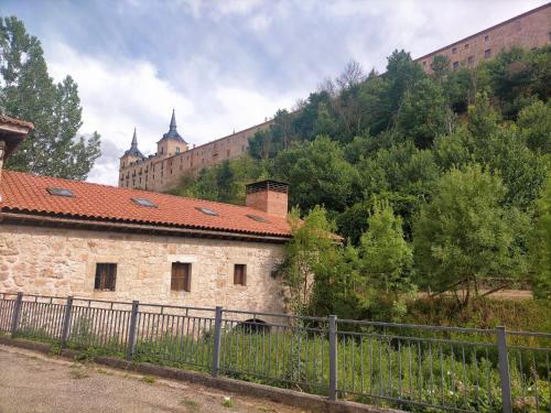 um antigo edifício de pedra com um castelo ao fundo em Albergue Molino Solacuesta em Lerma