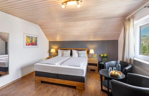 a bedroom with a bed and a table and chairs at Hotel Garni Sonnengruss in Hagnau