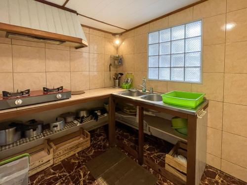 eine kleine Küche mit einem Waschbecken und einem Fenster in der Unterkunft Relais du Volcan in La Plaine des Cafres