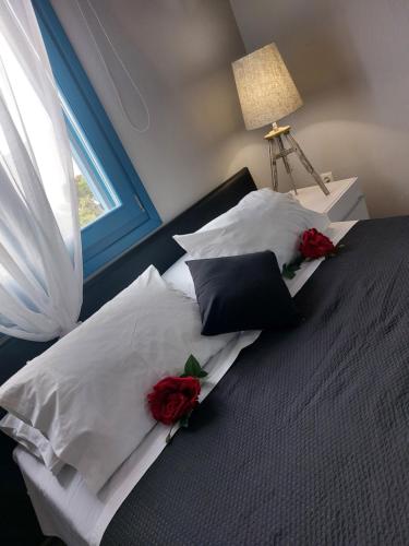 a bed with white pillows and red roses on it at George's point of view in Naousa