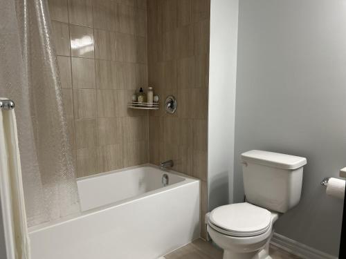 uma casa de banho com um WC, uma banheira e um WC. em Kolopizo Lounge - Standard Room em Ottawa