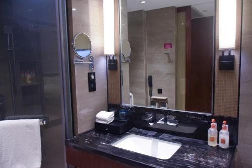 ein Badezimmer mit einem Waschbecken und einem großen Spiegel in der Unterkunft Neodalle Zhangjiajie Wulingyuan in Zhangjiajie