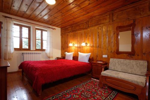 a bedroom with a red bed and a chair at Yovina House Zheravna in Zheravna