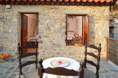 a table and chairs in front of a stone house at A small paradise in Mani with local hospitality in Órva
