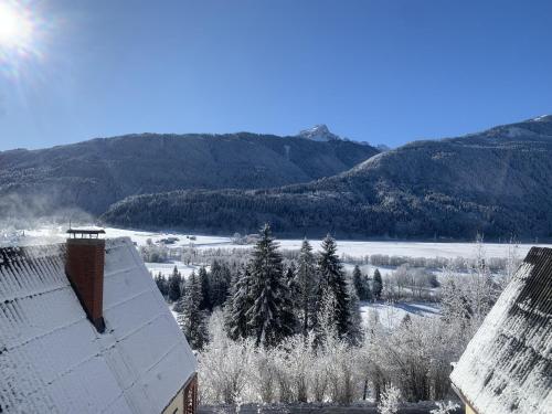 a snow covered roof of a building with mountains in the background at Das kleine Feriendorf in Carinthia