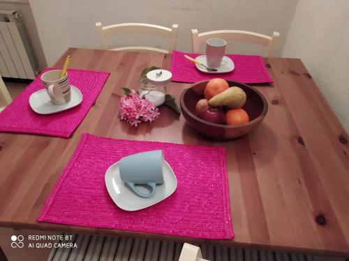 a wooden table with pink napkins and a bowl of fruit at Casa di Ermes in Sestri Levante