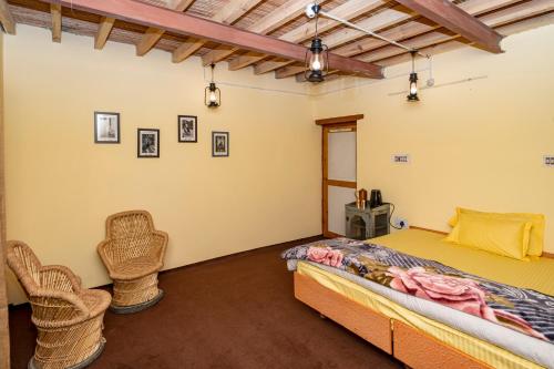 a bedroom with a bed and two wicker chairs at NotOnMap- Norbu Homestay Kaza in Kaza