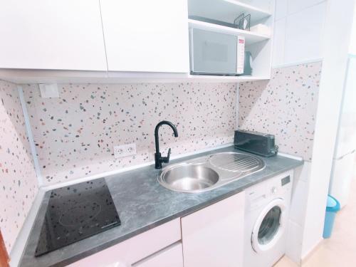 eine Küche mit einer Spüle und einer Waschmaschine in der Unterkunft Golden Estudio in Málaga