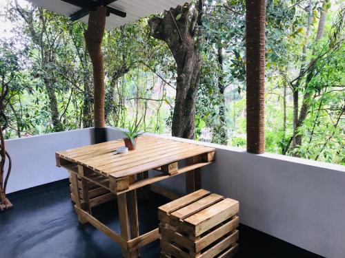 a wooden table and bench on a balcony with trees at Sandaro Rest Inn in Ella
