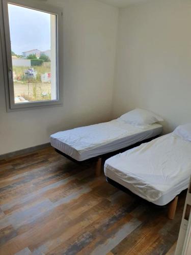 deux lits dans une chambre avec une fenêtre dans l'établissement MISTRAL ABBA a 500m de la plage, à Saint-Vincent-sur-Jard
