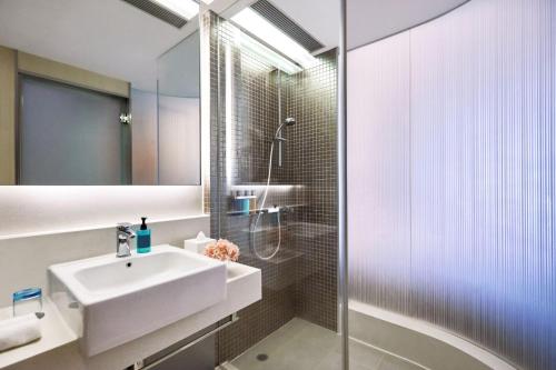 a white bathroom with a sink and a shower at Vega Suites in Hong Kong