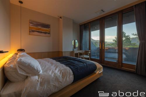 a bedroom with a bed and a large window at abode villa GORA 八代別邸 in Onsensō