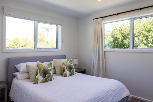 una camera con un letto bianco e due finestre di The Apartment at Arrowtown ad Arrowtown