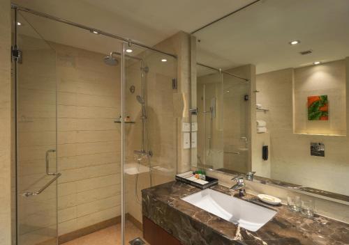 a bathroom with a sink and a glass shower at The Acacia Hotel & Spa in Candolim