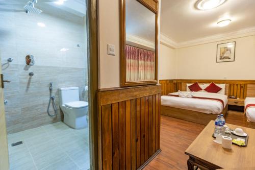Habitación de hotel con cama y baño con ducha. en Hotel Sekai, en Katmandú