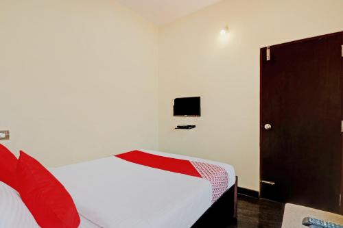 Schlafzimmer mit einem weißen Bett und roten Kissen in der Unterkunft OYO Blooms Inn in Bangalore