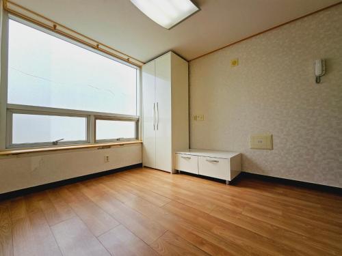 um quarto vazio com uma grande janela e pisos em madeira em D&D PineVill em Busan