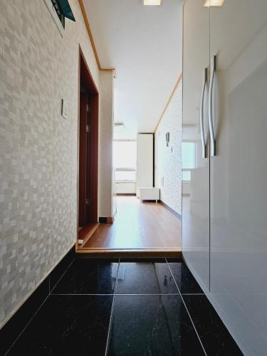 um corredor com piso em azulejo preto e uma porta em D&D PineVill em Busan