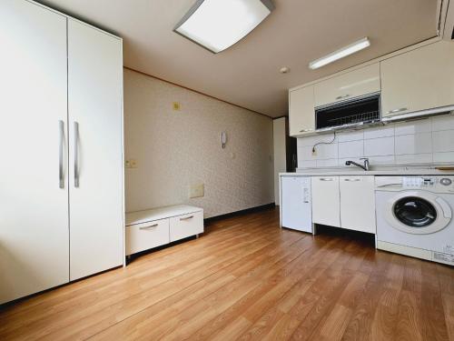 uma cozinha com máquina de lavar e secar roupa num quarto em D&D PineVill em Busan
