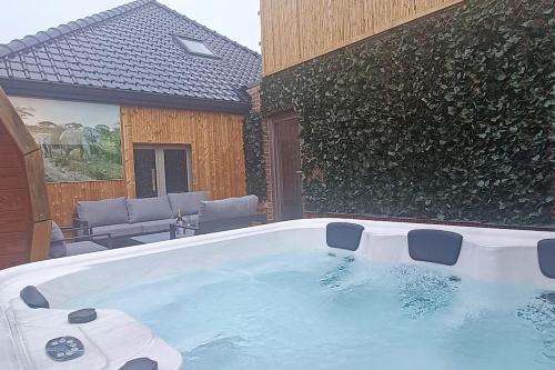 uma grande banheira de hidromassagem num quintal com um pátio em Stijlvol appartement met jacuzzi & sauna em Herk-de-Stad