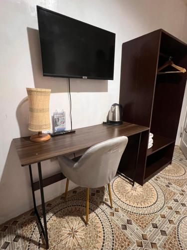 a desk with a chair and a television on a wall at Sunny Terrace in Baler