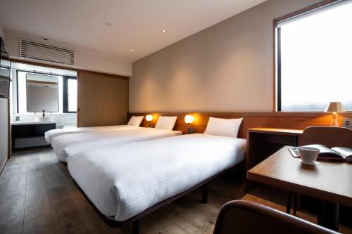 京都市にあるhotel Bell・Kyotoのベッド2台とデスクが備わるホテルルームです。