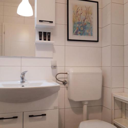 a white bathroom with a sink and a toilet at Sunshine Apartment in Bijeljina