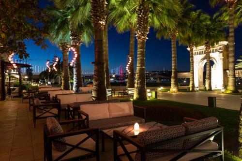 a row of tables and chairs with palm trees at night at Çırağan Palace Kempinski Istanbul in Istanbul