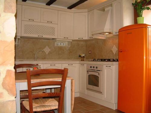 een keuken met witte kasten, een tafel en een koelkast bij Casa Roberto - Campagna Toscana vicino al mare in Castellina Marittima