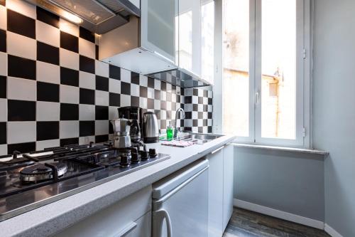 une cuisine avec un mur en damier noir et blanc dans l'établissement APPARTAMENTO CON TERRAZZINO AL PANTHEON, à Rome