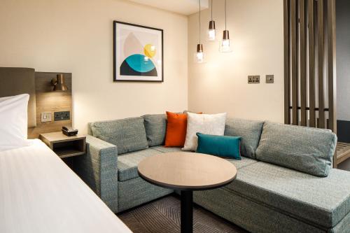 een woonkamer met een bank en een tafel bij Holiday Inn Manchester Airport, an IHG Hotel in Hale