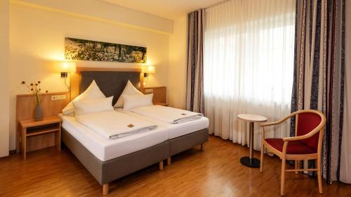 a hotel room with a bed and a chair at Hotel Löwengarten in Speyer